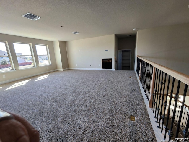 carpeted empty room with a textured ceiling