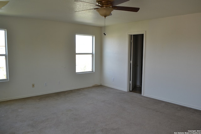 spare room with ceiling fan and light carpet