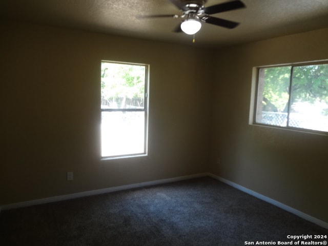 carpeted empty room with a textured ceiling, plenty of natural light, and ceiling fan