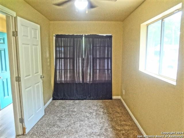 carpeted empty room featuring baseboards and ceiling fan