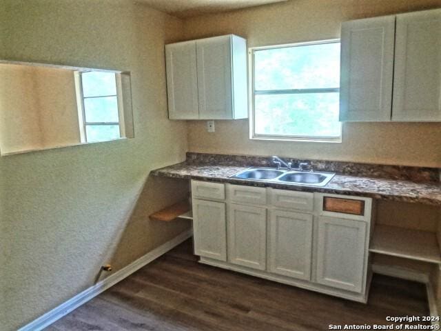kitchen with dark wood-type flooring, a sink, open shelves, white cabinetry, and baseboards