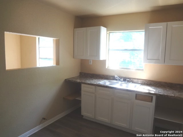 kitchen with dark wood-type flooring, white cabinets, and sink