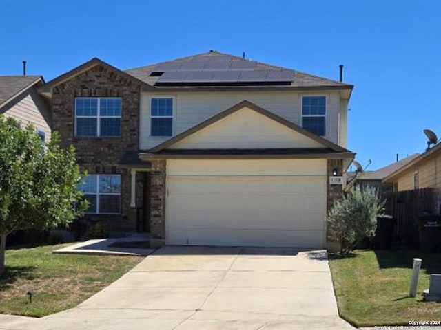 traditional-style home featuring roof mounted solar panels, a front lawn, concrete driveway, and a garage