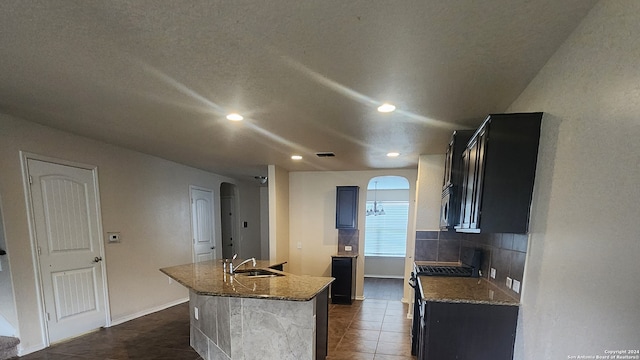 kitchen with a kitchen island with sink, dark tile patterned floors, electric range, and light stone countertops