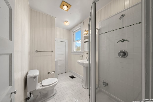 bathroom featuring tile patterned flooring, toilet, and a tile shower