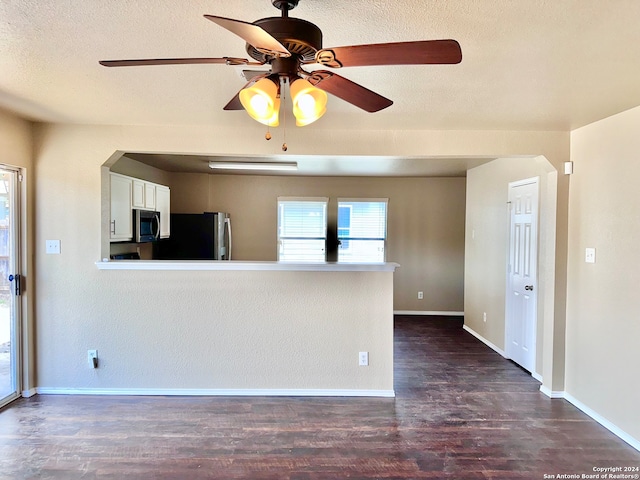 interior space with ceiling fan, a textured ceiling, dark wood-type flooring, white cabinetry, and stainless steel appliances