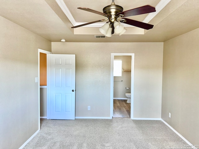 unfurnished bedroom featuring light carpet, a textured ceiling, ensuite bathroom, and ceiling fan