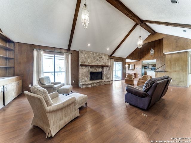 living room with lofted ceiling with beams, dark hardwood / wood-style flooring, a stone fireplace, wood walls, and a textured ceiling