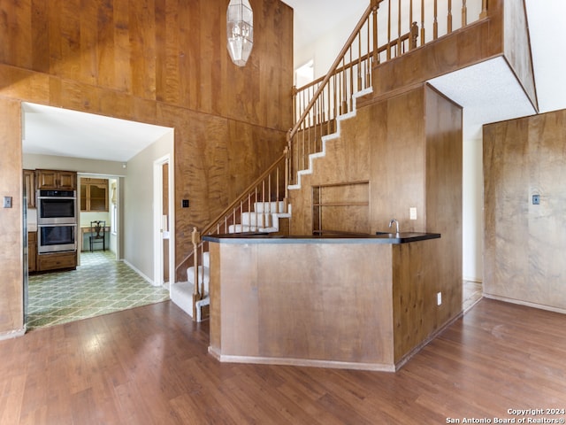 stairway with a high ceiling, hardwood / wood-style floors, and wooden walls