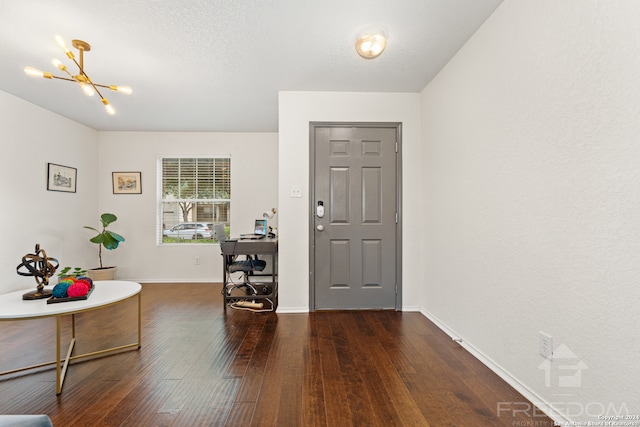 foyer with a textured ceiling, a notable chandelier, and dark wood-type flooring