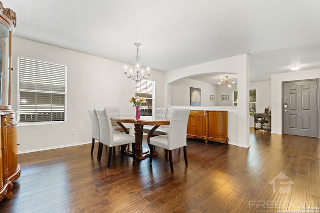 dining area with a textured ceiling, dark hardwood / wood-style floors, and an inviting chandelier