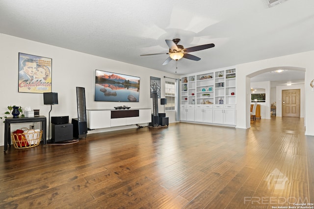 living room featuring a textured ceiling, dark hardwood / wood-style flooring, ceiling fan, and built in shelves