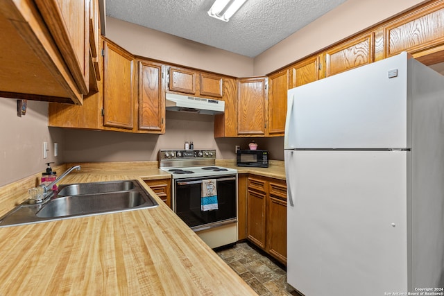 kitchen featuring white refrigerator, electric range oven, sink, and a textured ceiling