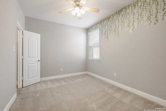 spare room with ceiling fan and light carpet