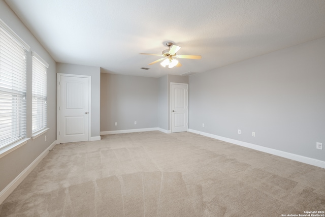 carpeted spare room with a textured ceiling and ceiling fan