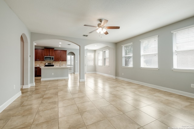 unfurnished living room with a textured ceiling, ceiling fan, and light tile patterned flooring