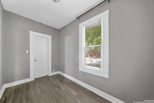 empty room featuring plenty of natural light and dark hardwood / wood-style flooring