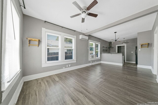 143 Paul St, San Antonio, TX 78203 - unfurnished living room with ceiling fan with notable chandelier, baseboards, dark wood-style floors, and a wall mounted air conditioner