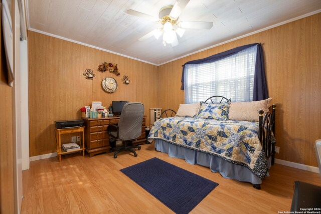 bedroom featuring ornamental molding, wooden walls, ceiling fan, and hardwood / wood-style floors