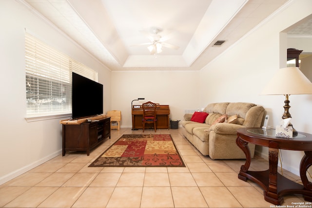 tiled living room with crown molding, a tray ceiling, and ceiling fan