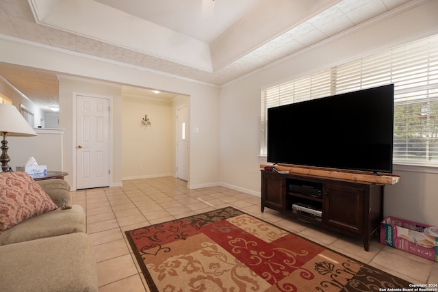 tiled living room with ornamental molding and a tray ceiling