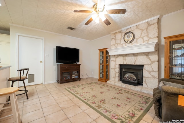 living room with ornamental molding, ceiling fan, and a stone fireplace