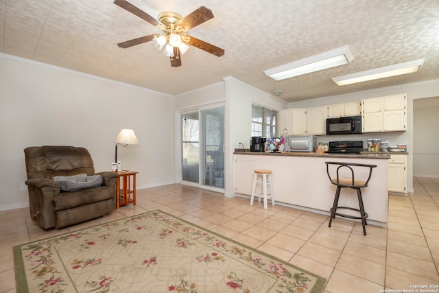 kitchen featuring kitchen peninsula, a kitchen bar, black appliances, light tile patterned floors, and ceiling fan