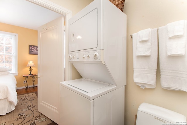 laundry area featuring hardwood / wood-style floors and stacked washing maching and dryer