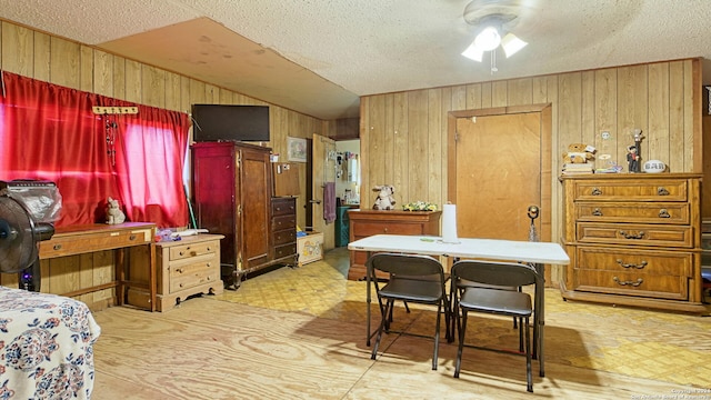 bedroom featuring wood walls, ceiling fan, and a textured ceiling