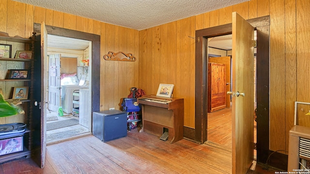 interior space with a textured ceiling, wooden walls, and hardwood / wood-style floors