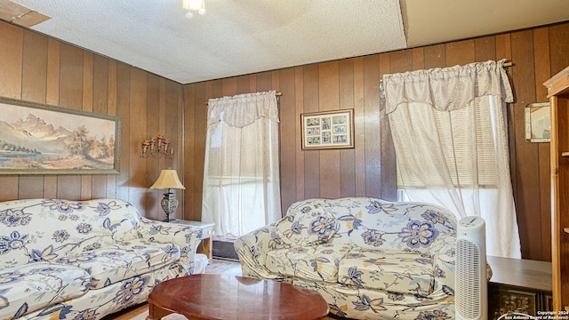 living room featuring a textured ceiling and wooden walls