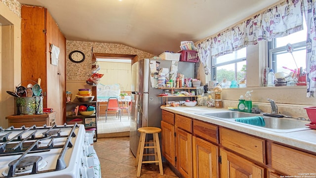 kitchen featuring lofted ceiling, light tile patterned flooring, sink, and white gas range oven