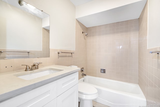 full bathroom featuring vanity, tile walls, toilet, decorative backsplash, and tiled shower / bath combo