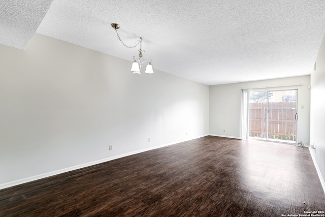 empty room with hardwood / wood-style floors, a chandelier, and a textured ceiling