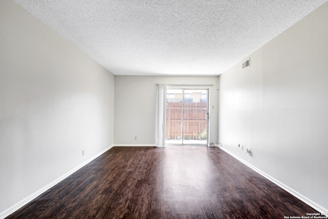 empty room featuring dark wood-type flooring and a textured ceiling