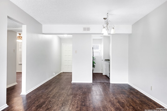 unfurnished room featuring dark hardwood / wood-style flooring, a chandelier, and a textured ceiling