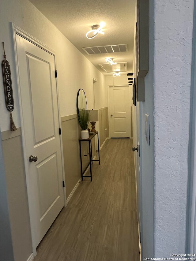 corridor featuring hardwood / wood-style flooring and a textured ceiling