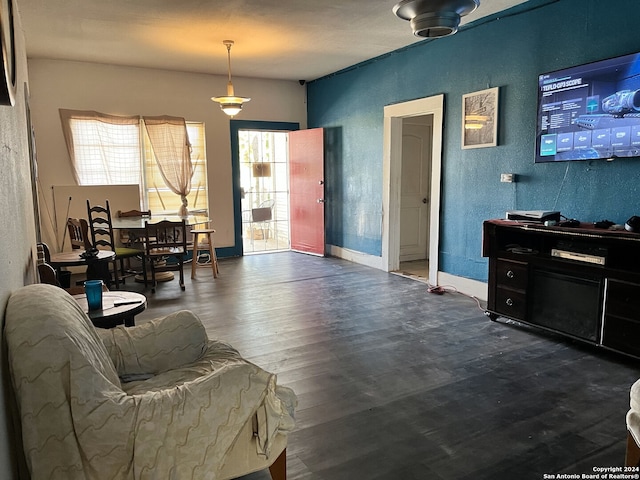 living area with a textured wall, baseboards, and dark wood finished floors