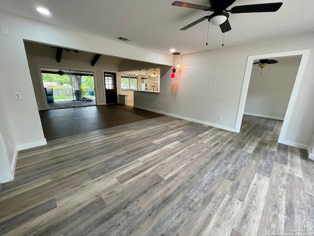 unfurnished living room featuring beamed ceiling, ceiling fan, and wood-type flooring