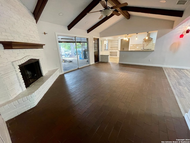 unfurnished living room with ceiling fan, a brick fireplace, and lofted ceiling with beams