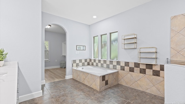 bathroom featuring a relaxing tiled tub and tile patterned flooring