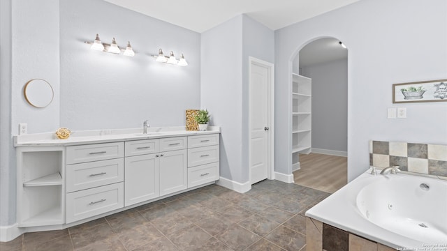 bathroom with tiled tub, vanity, and tile patterned floors