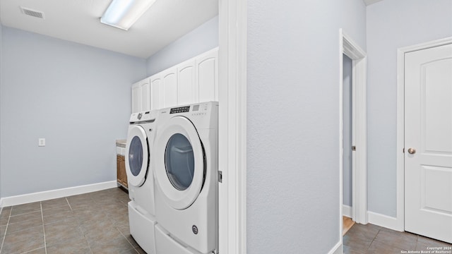 washroom featuring cabinets, washing machine and clothes dryer, and tile patterned floors