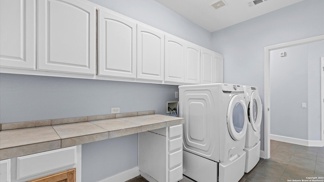 clothes washing area featuring cabinets, light tile patterned floors, and washing machine and clothes dryer