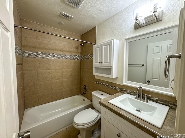 full bathroom featuring tiled shower / bath, backsplash, toilet, vanity, and a textured ceiling