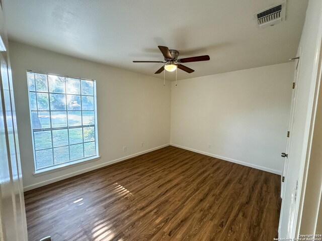 spare room featuring a wealth of natural light, ceiling fan, and dark hardwood / wood-style floors