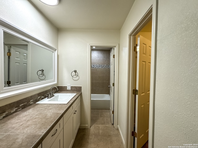 bathroom with tile patterned flooring, vanity, and tiled shower / bath combo