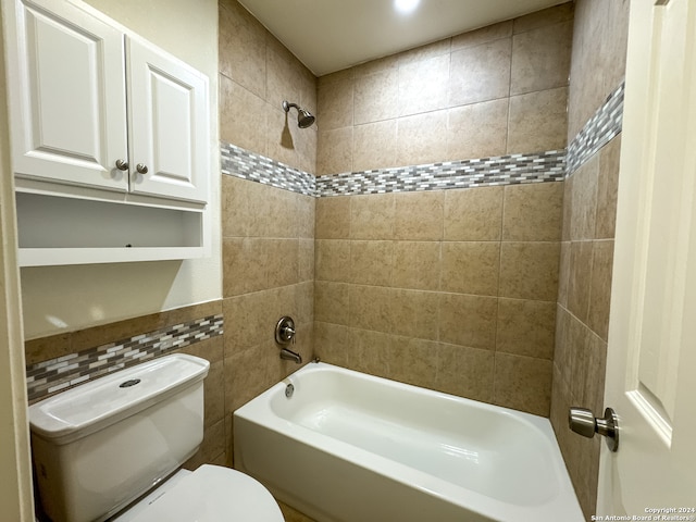 bathroom with tiled shower / bath, tile walls, and toilet