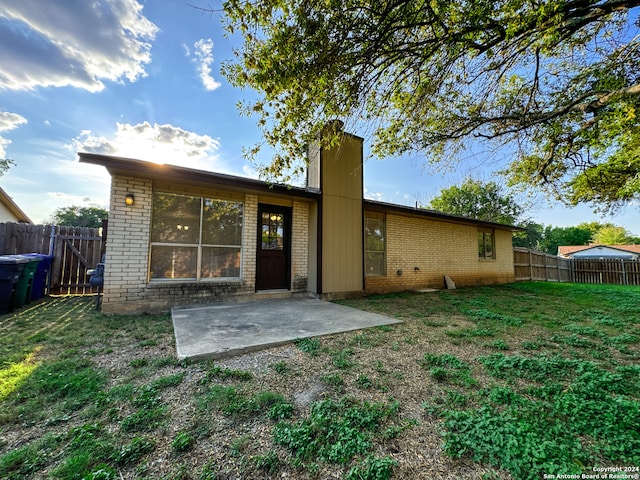 back of property featuring a lawn and a patio