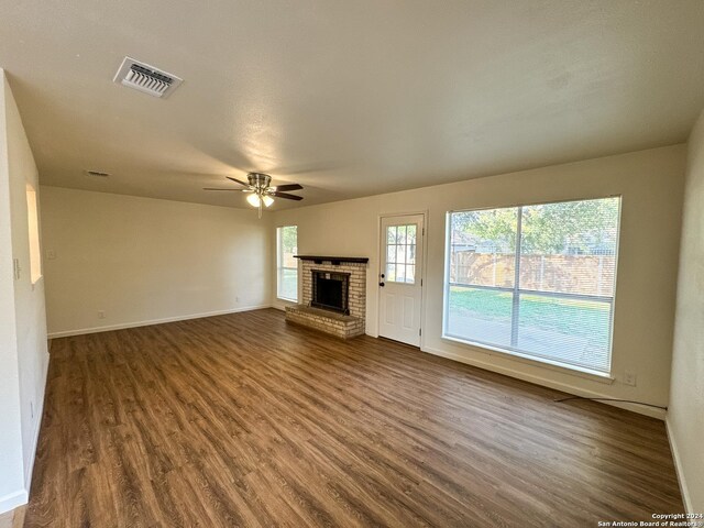 unfurnished living room featuring ceiling fan, dark hardwood / wood-style floors, and a brick fireplace